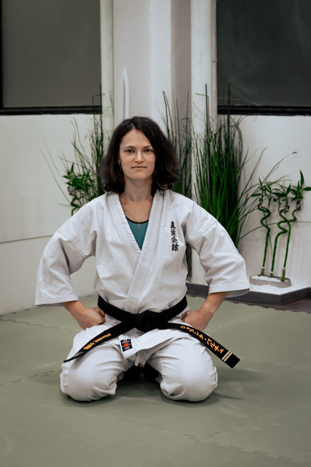 Jolanta Balčė klūpi ant tatamio su baltu gi ir juodu diržu